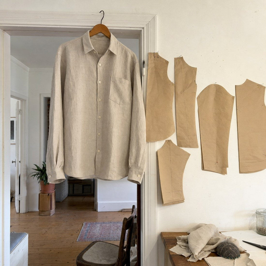 A finished linen shirt on a hanger beside the pattern it came from